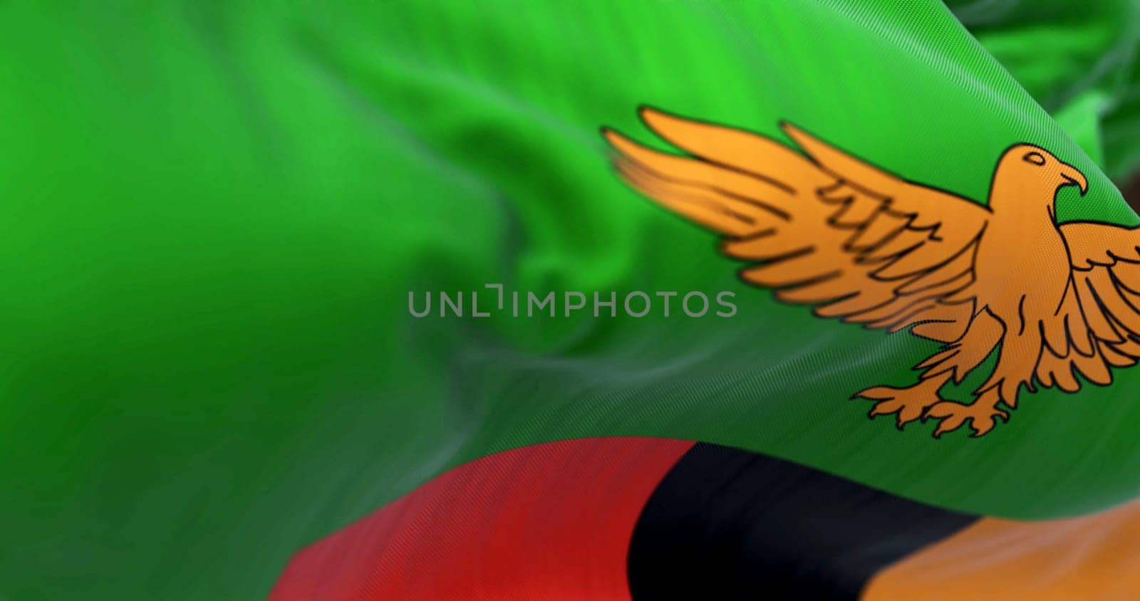 Zambia national flag waving. Green with an orange eagle in flight over a block of three vertical stripes in red, black, and orange. Fabric textured background. Selective focus. 3d illustration render