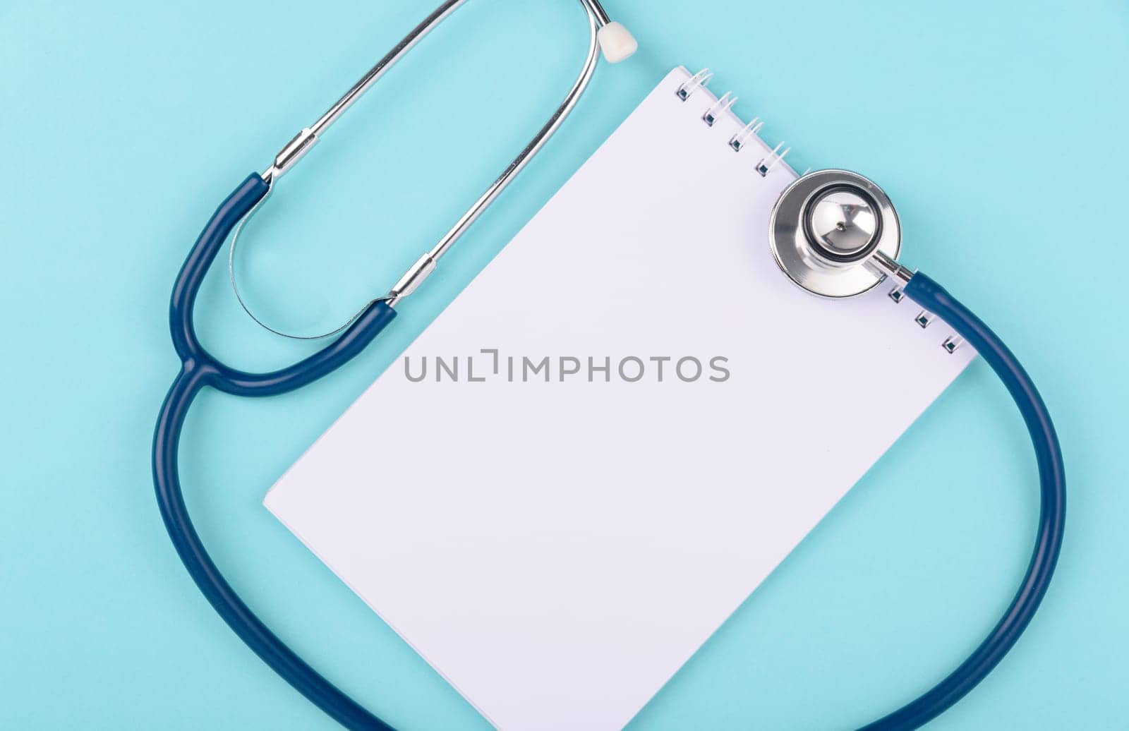 Doctor's Day Concept, Top view, doctor stethoscope and white peper note book diagnosis of heart disease isolated on blue background with copy space, Medical and Health care insurance