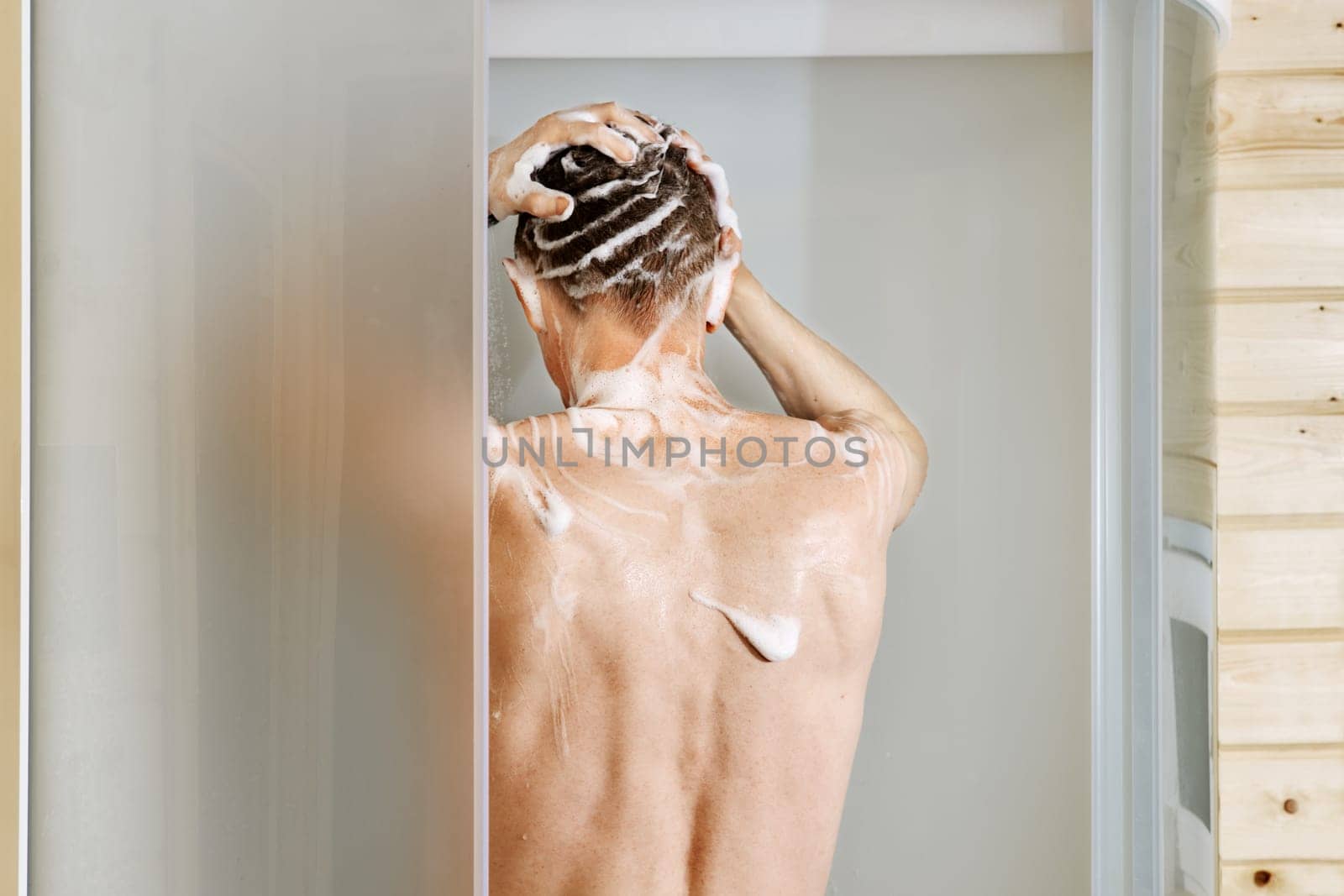 Back view of a man washing hair in the shower