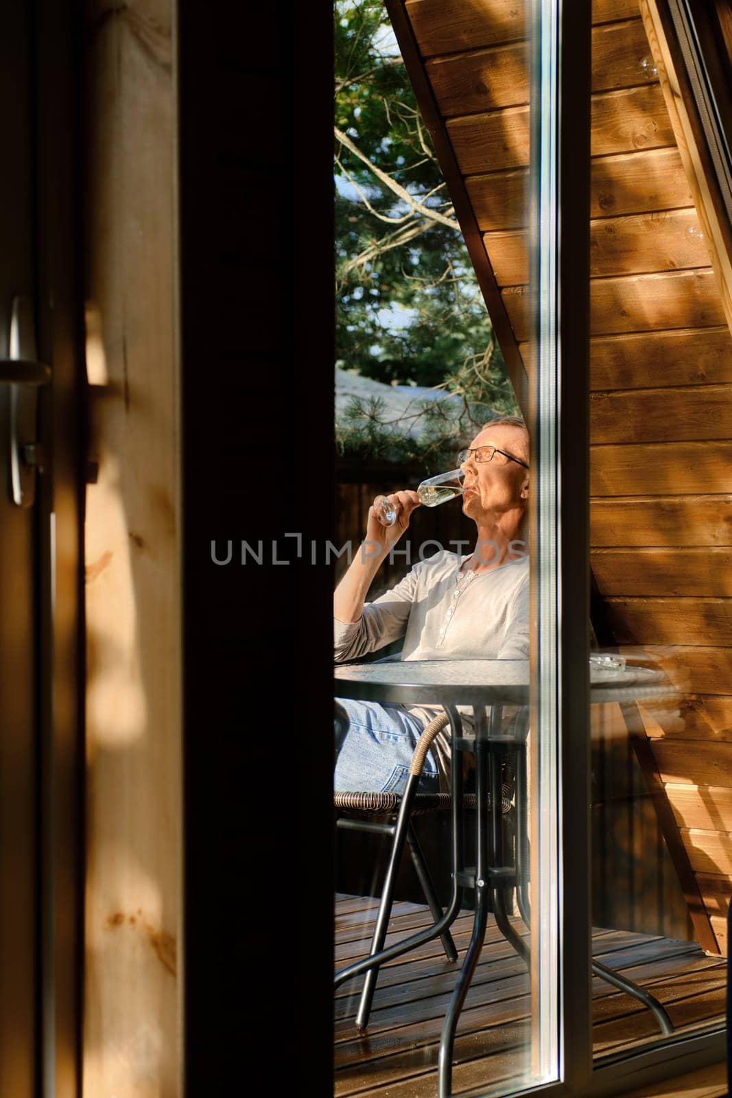 Man sits on terrace in sunny day and drinks cold prosecco