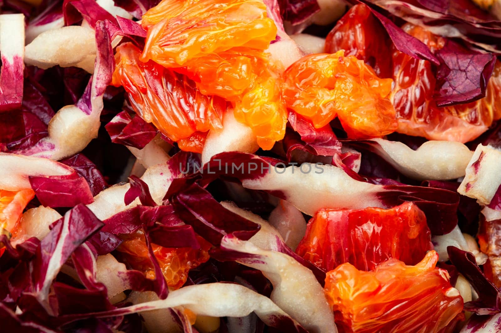 Tasty salad with chicory or radicchio, grapefruit and pine nuts on the table