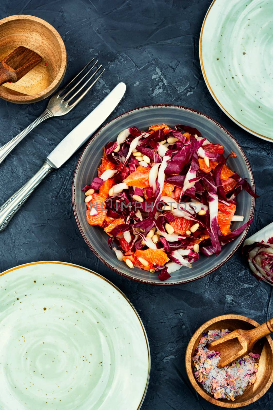 Tasty salad with chicory or radicchio, grapefruit and pine nuts on the table
