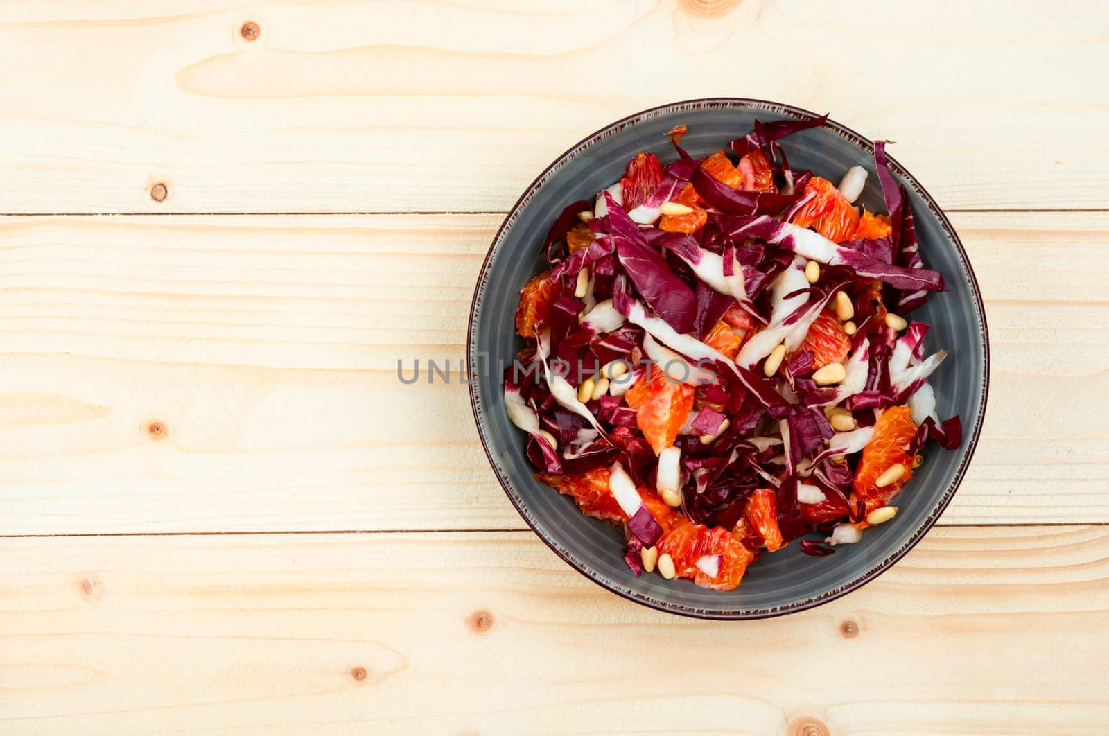 Tasty salad with chicory or radicchio, grapefruit and pine nuts on the table