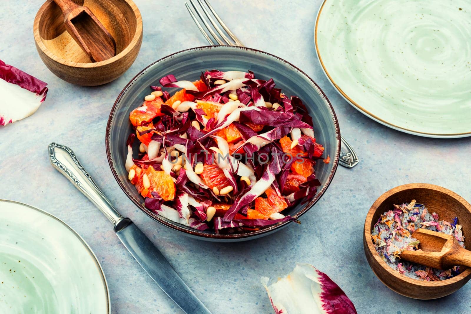 Tasty salad with chicory or radicchio, grapefruit and pine nuts on the table
