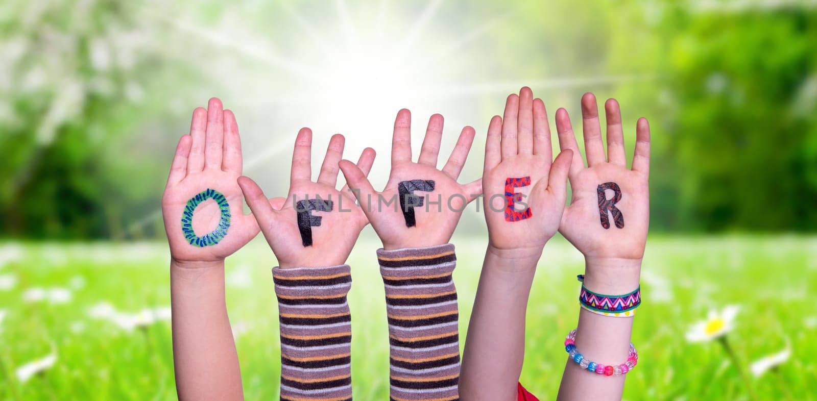 Children Hands Building Colorful English Word Offer. Sunny Green Grass Meadow As Background.