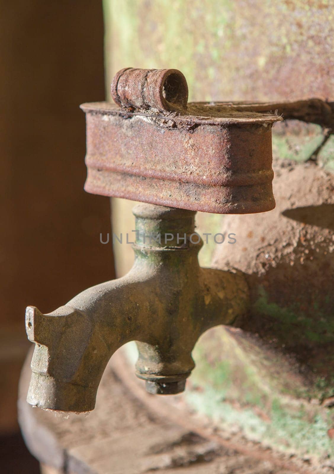 Rusty faucet detail from old olive oil drum. Old farm background