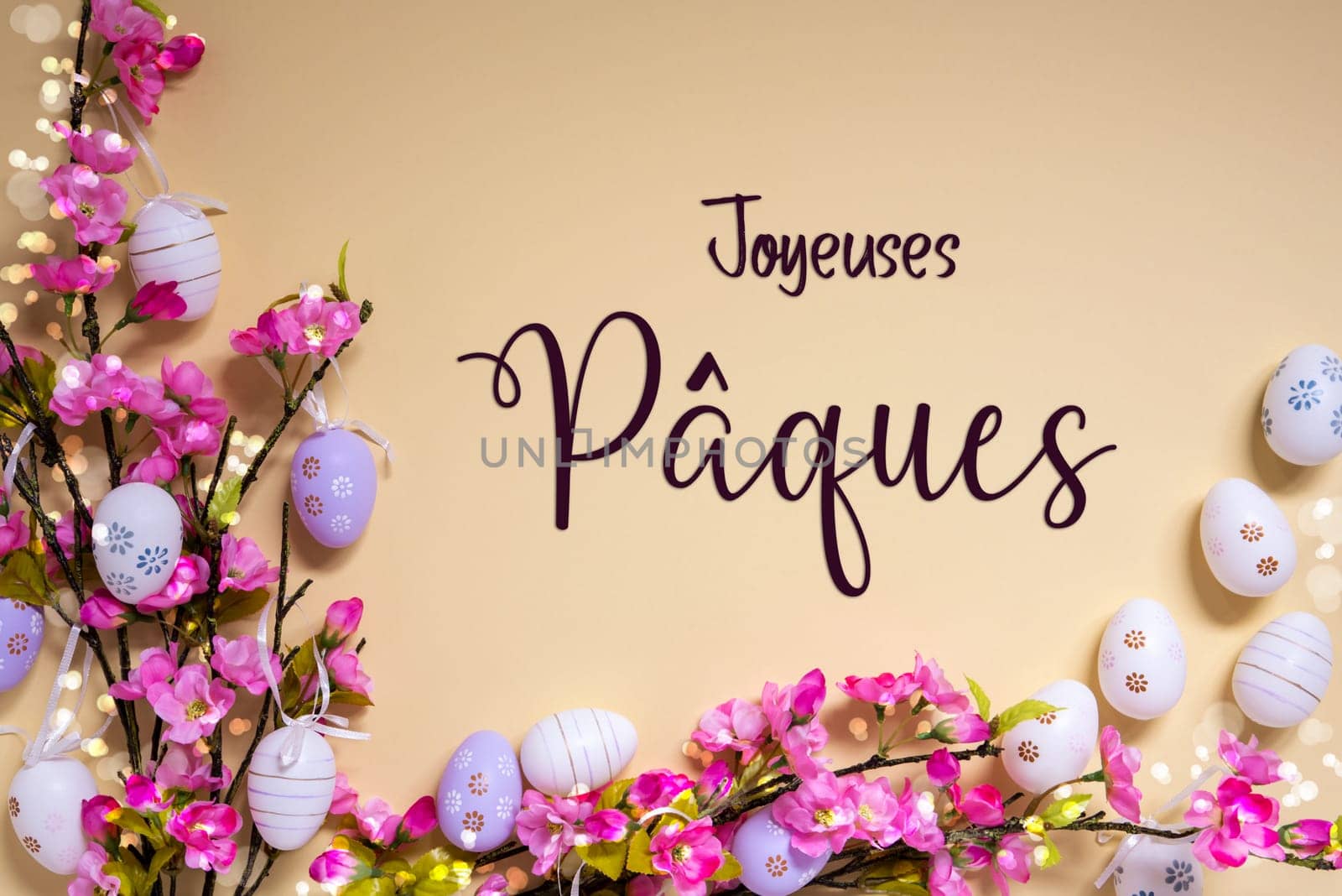 French Text Joyeuses Paques Means Happy Easter On Beige Background. Pink And Purple, Shiny And Bright Spring Flower Arrangement With Easter Egg Decoration.