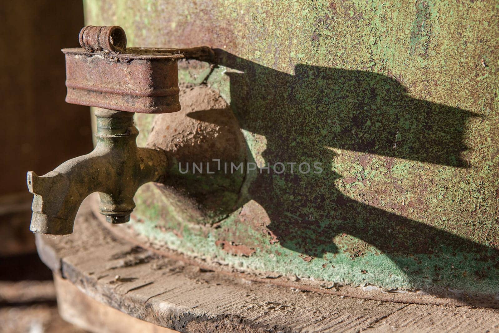 Rusty faucet detail from old olive oil drum. Old farm background