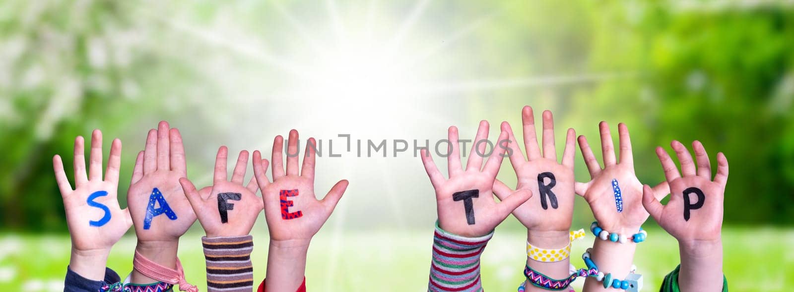 Children Hands Building Colorful English Word Safe Trip. Summer, Sunny Green Grass Meadow As Background