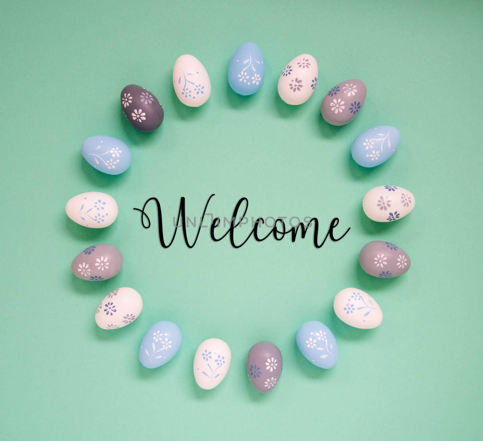 Flat Lay With English Text Welcome. Easter Egg Arrangement, Decoration And Ornament. Light Green Paper Background