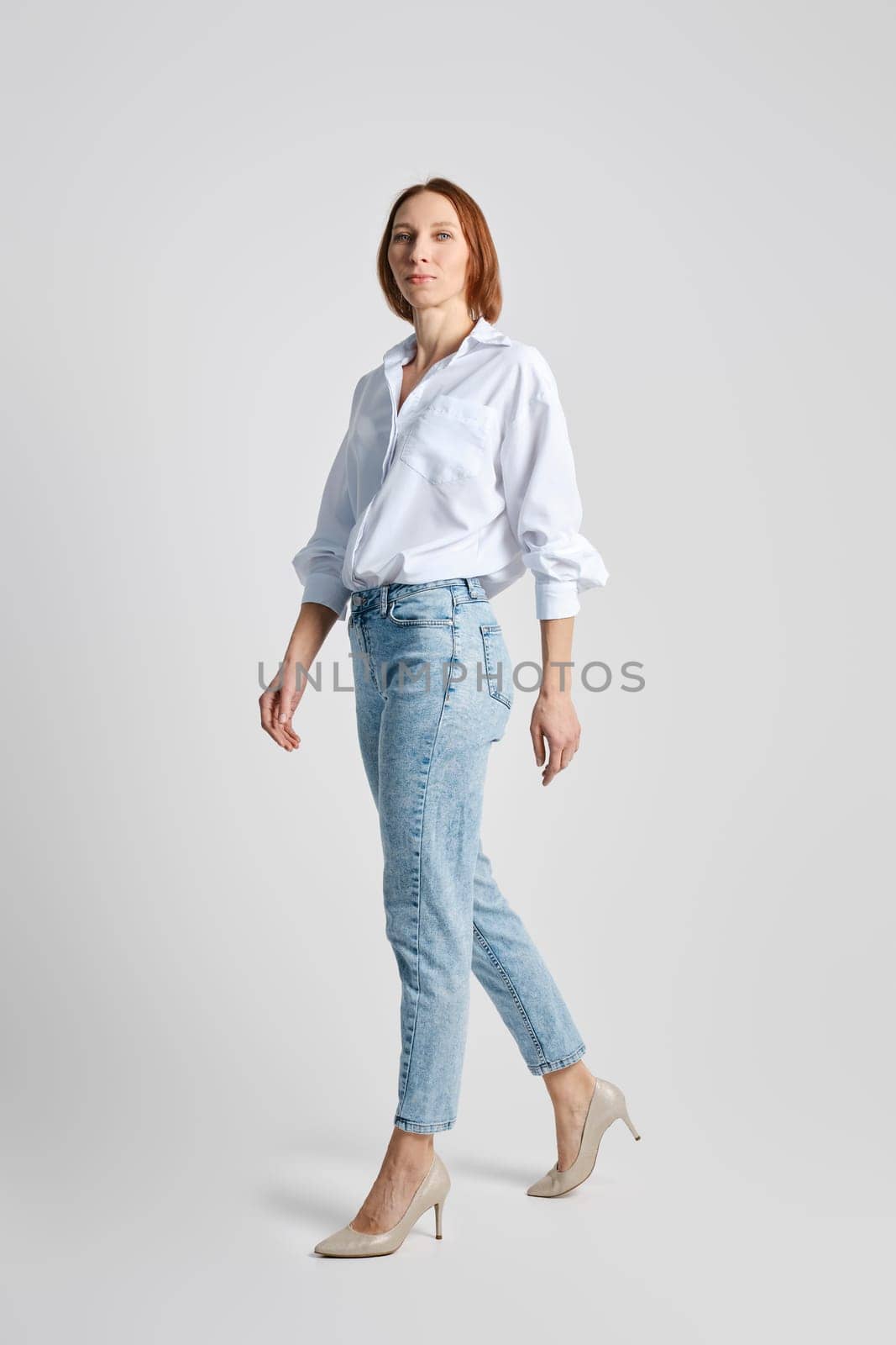 Trendy senior woman walking in grey studio