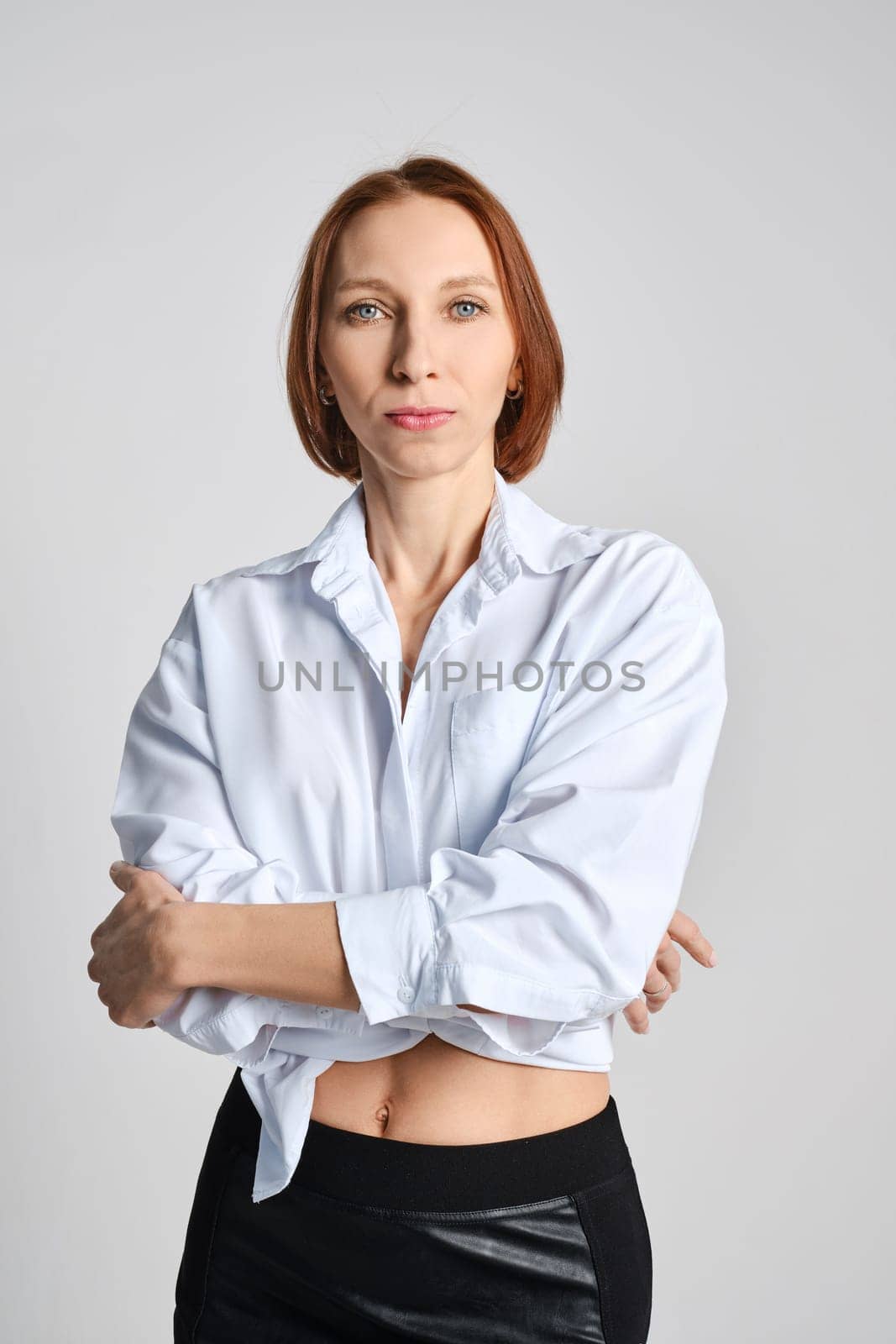 Studio portrait of adult woman with folded arms on grey background