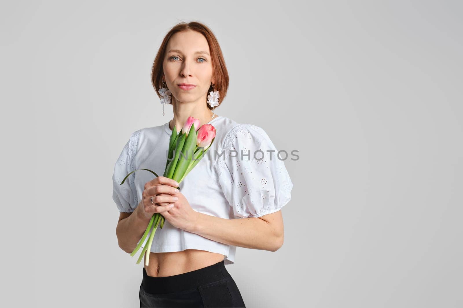 Cheerful adult woman hugging tulip flowers