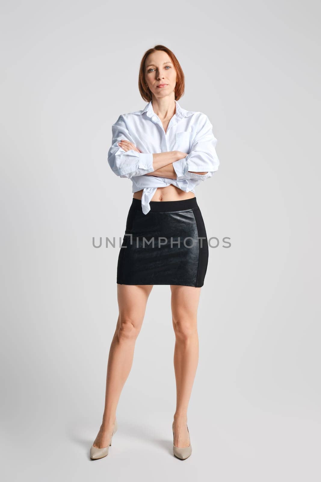 Full length studio portrait of middle aged woman in mini skirt and shirt