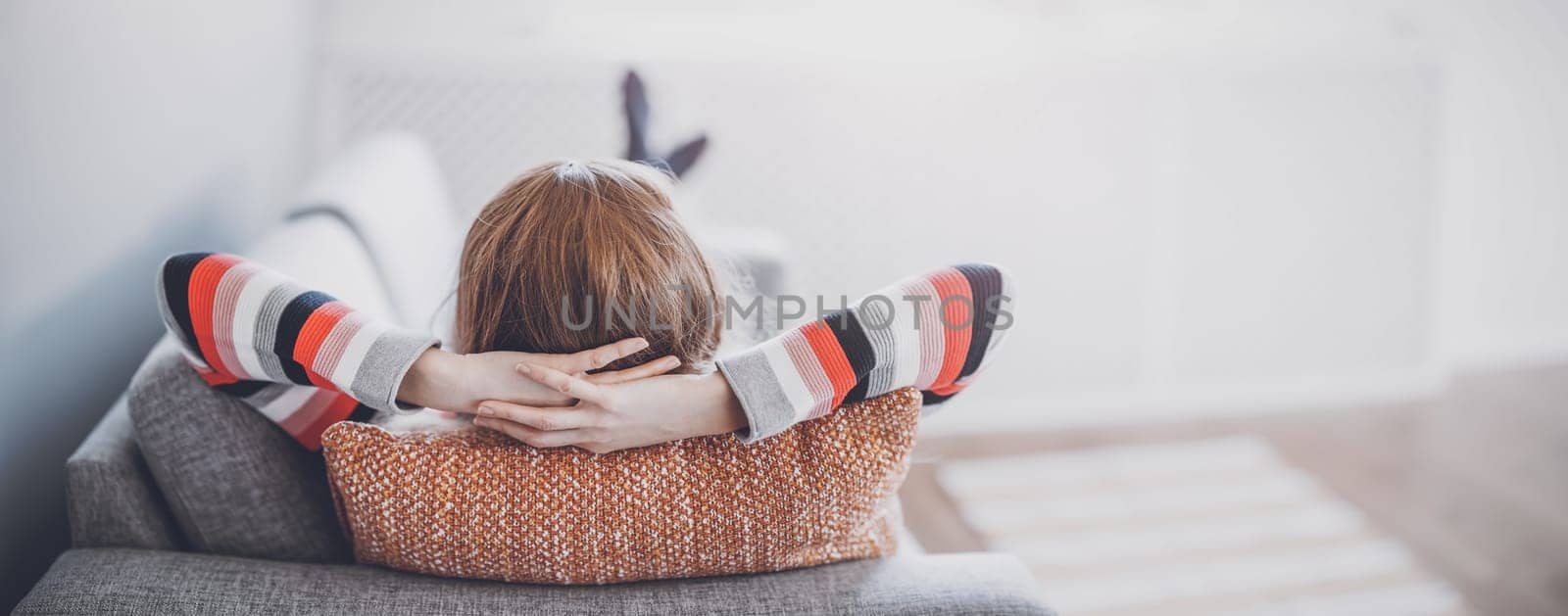 Tired woman lying down on the couch after workday. Panoramic view of the home interior.