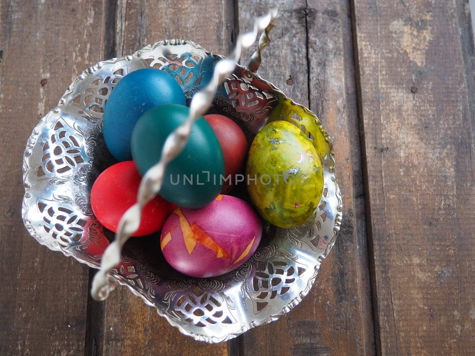 Easter colored eggs in an old metal candy bowl on a wooden table. Easter, the Resurrection of Christ, the Bright Resurrection of Christ, the most ancient and Christian holiday.
