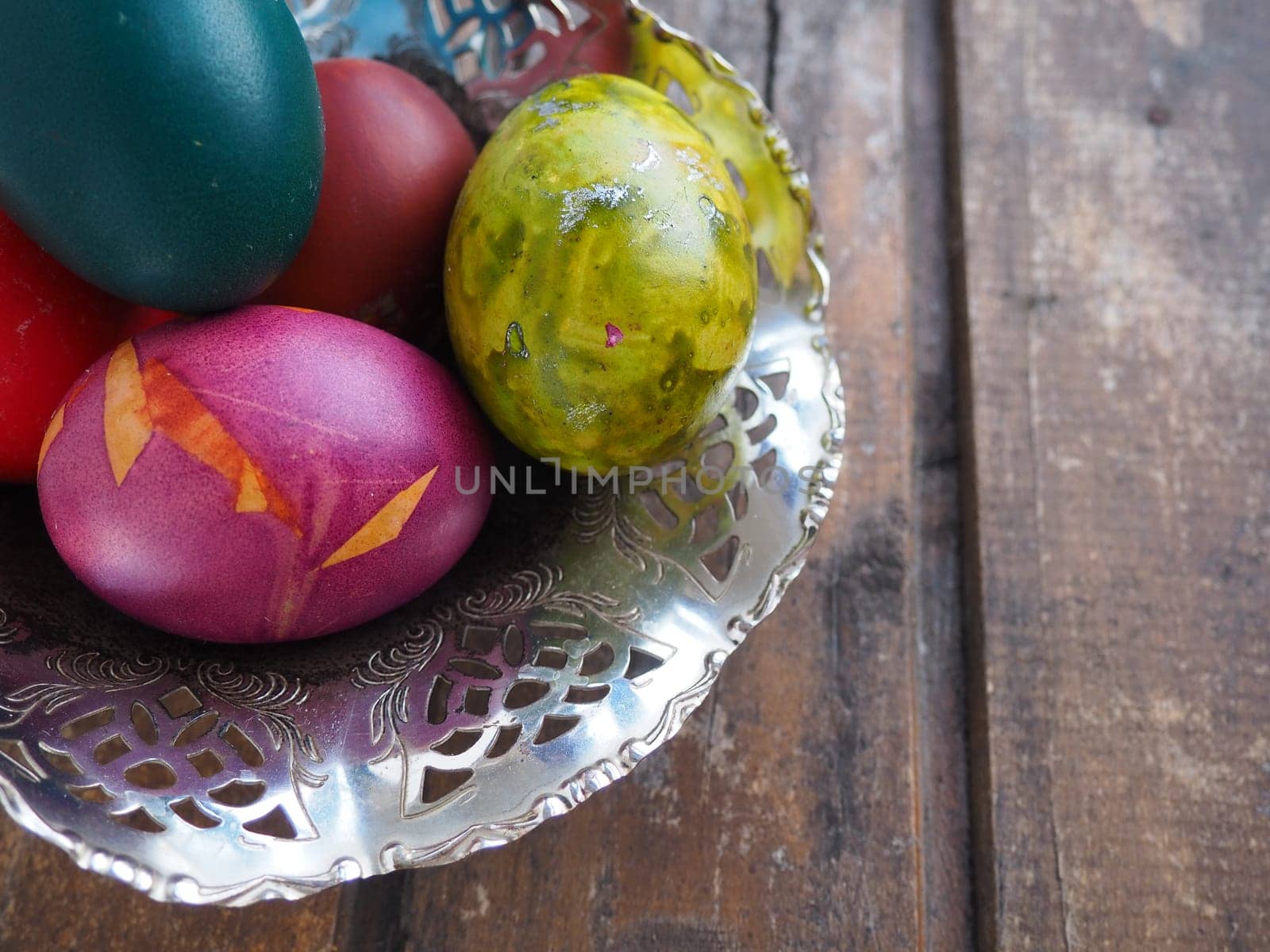 Easter colored eggs in an old metal candy bowl on a wooden table. Easter, the Resurrection of Christ, the Bright Resurrection of Christ, the most ancient and Christian holiday.