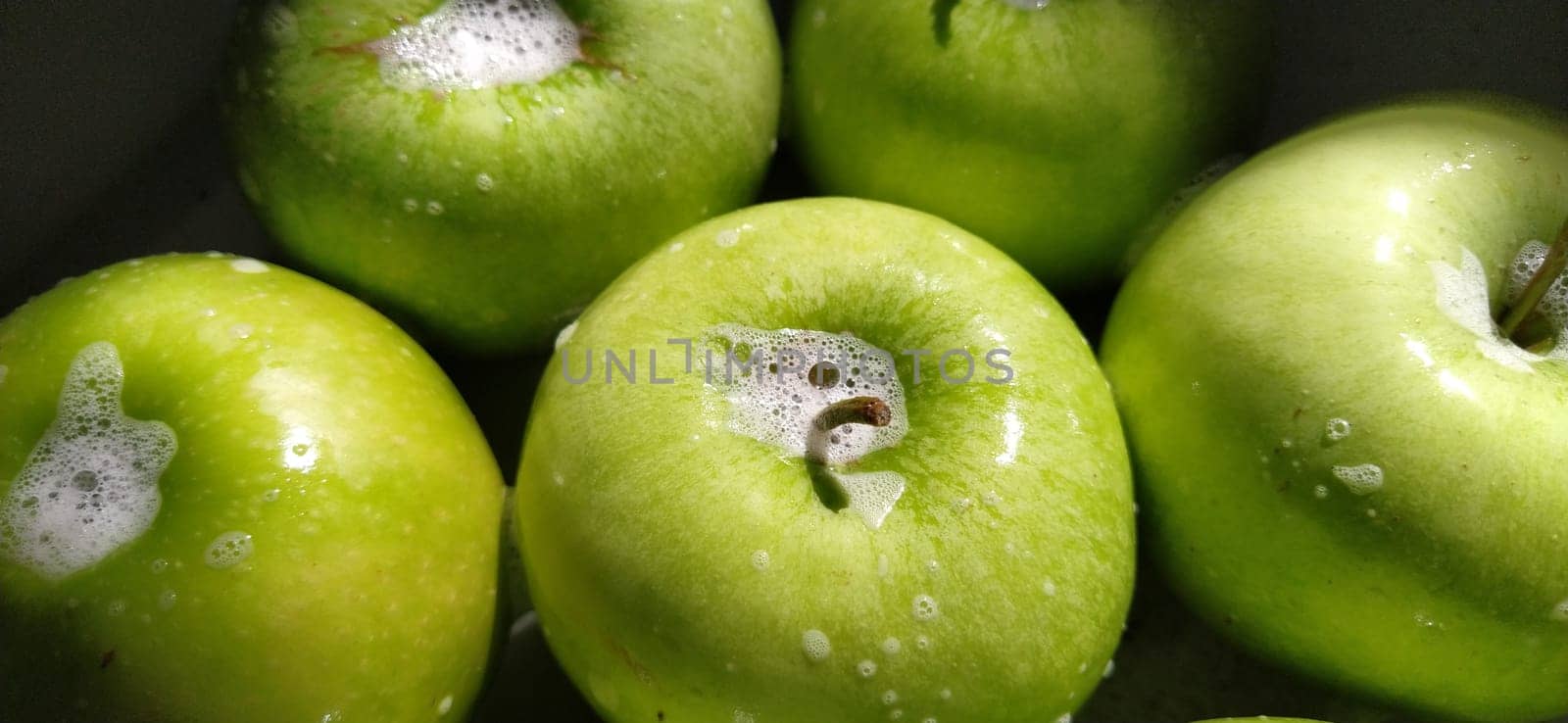 Wet soapy green apples. Thoroughly wash vegetables and fruits with water and soap. Prevention of infectious diseases. Apples close up. Vegetarianism. High glycemic index. Soapy foam sparkles in sunlight.