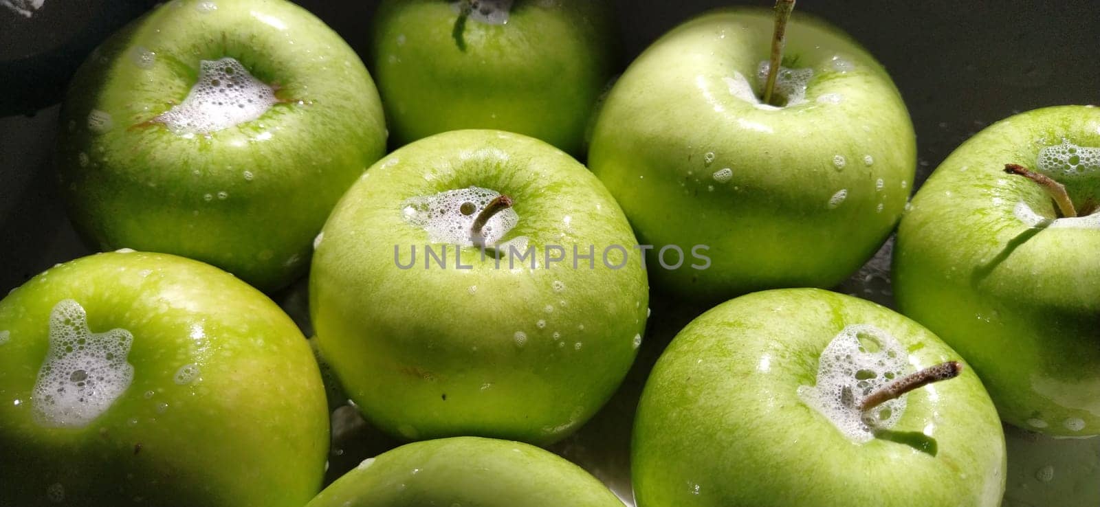 Wet soapy green apples. Thoroughly wash vegetables and fruits with water and soap. Prevention of infectious diseases. Apples close up. Vegetarianism. High glycemic index. Soapy foam sparkles in sunlight.