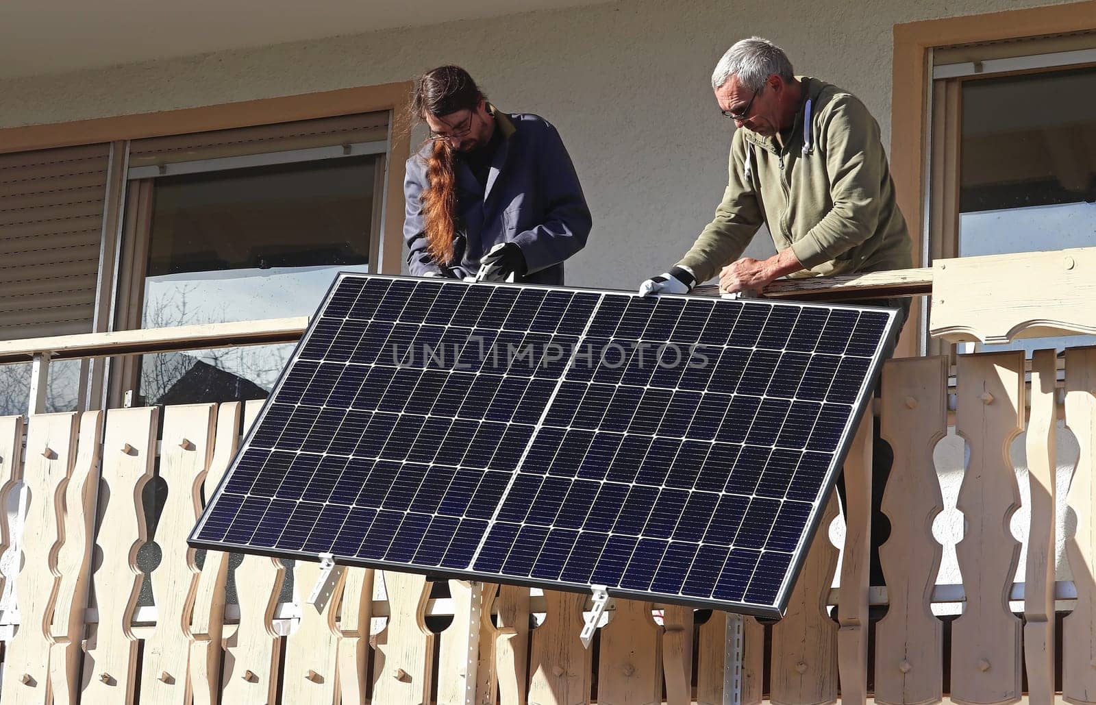 Two men assemble a balcony power plant to generate electricity