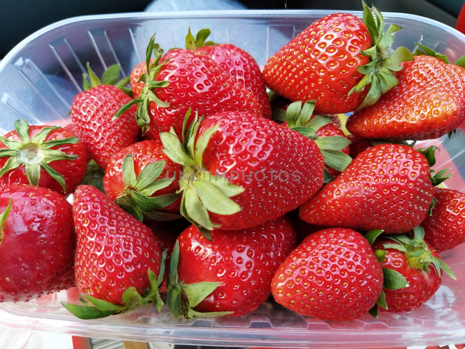 Fresh strawberries in a transparent plastic container. Beautiful red berries of garden strawberry.