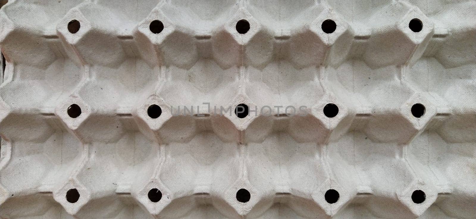 cardboard container for eggs close-up. Smooth rows, forms for laying eggs. Abstraction with convex and indented elements. Light and shadow. Rounded holes. Banner