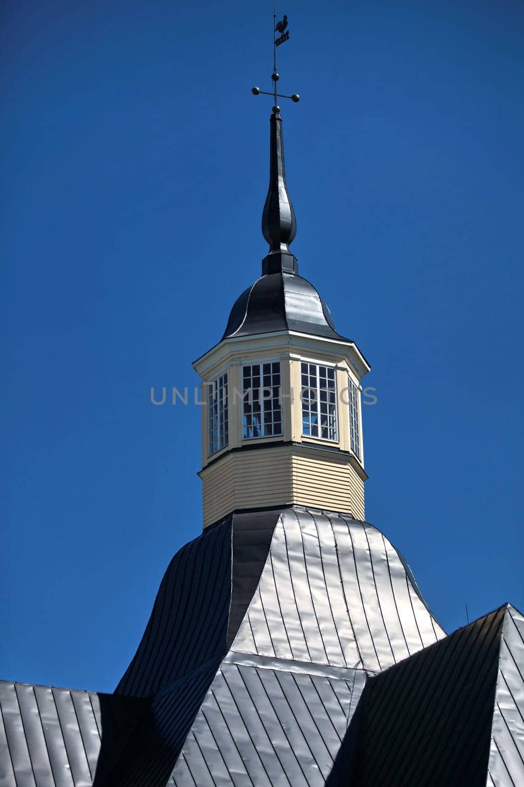 pointed spire with cross and weather vane, high in the blue sky