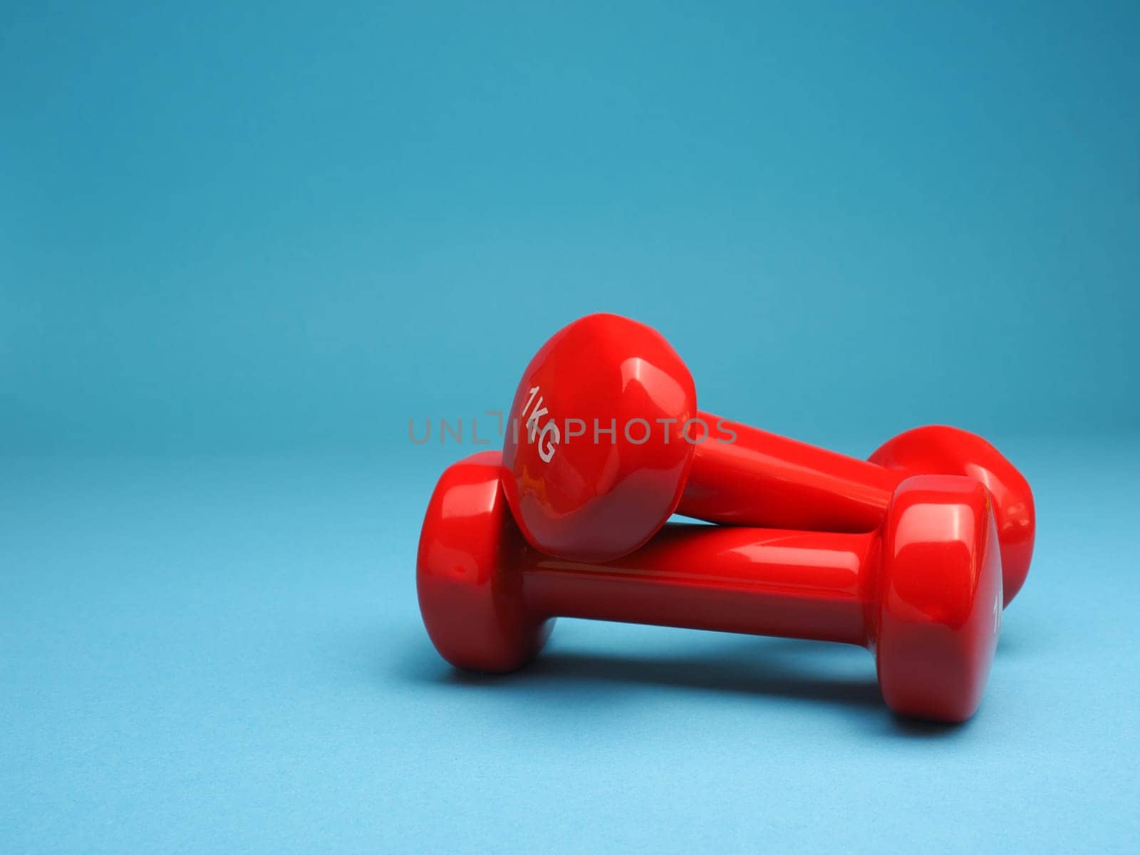Red dumbbells on a blue background, space for your text, fitness or diet concept