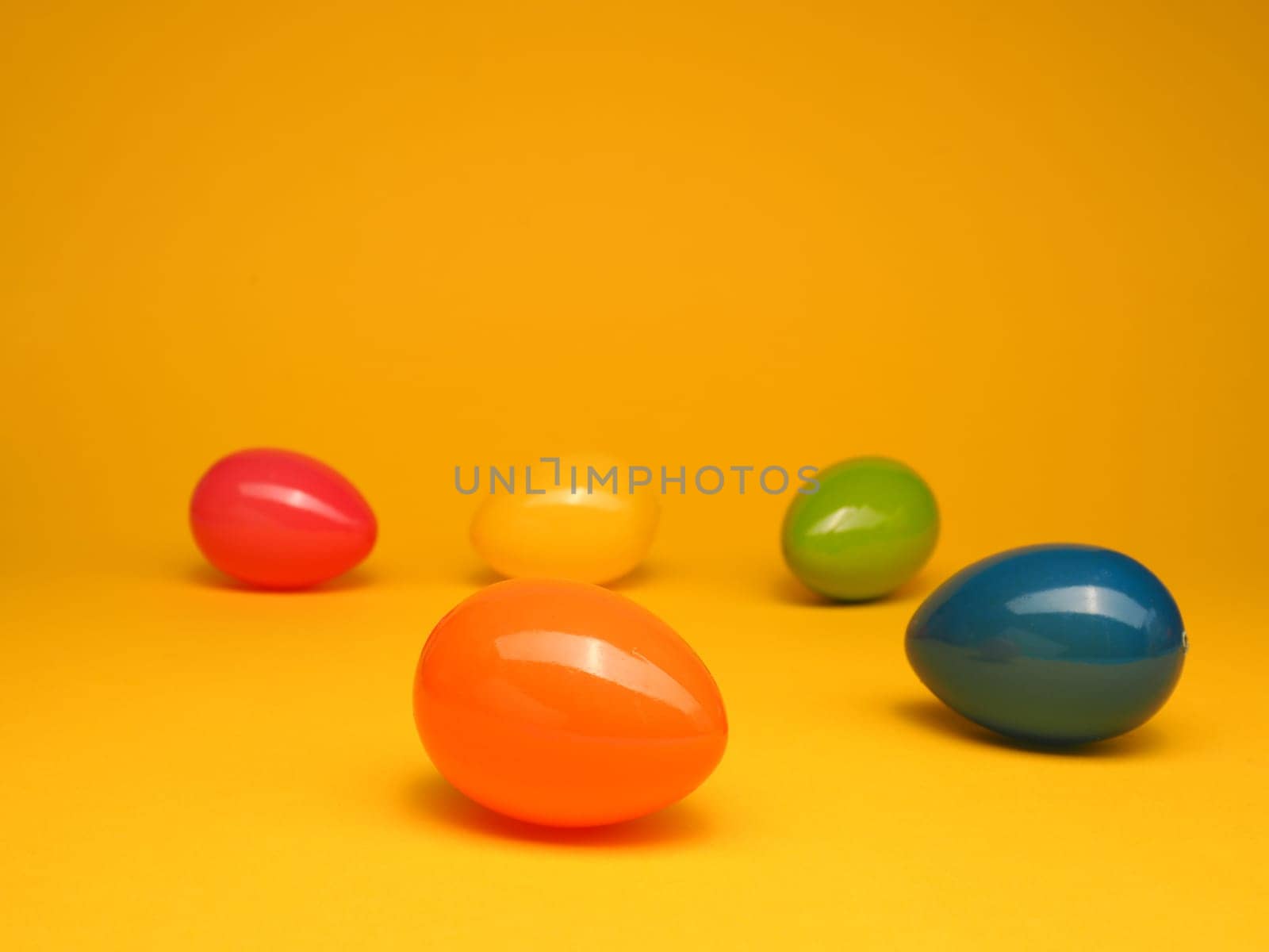 Colorful plastic Easter eggs on a yellow studio background, Happy Easter concept backdrop