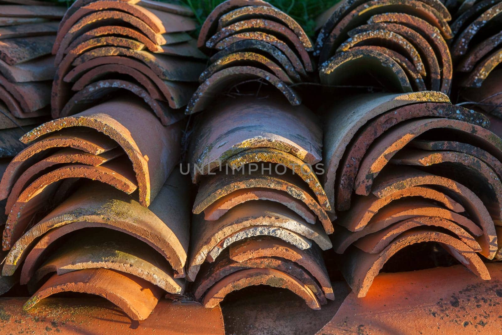 Piled of used mediterranean roof tiles with sunrise sun. Selective focus