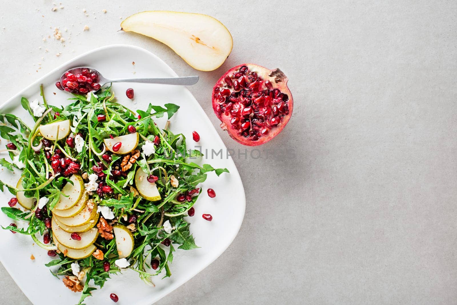 Healthy dandelion salad with pear fruit, pomegranate and fresh cheese close up