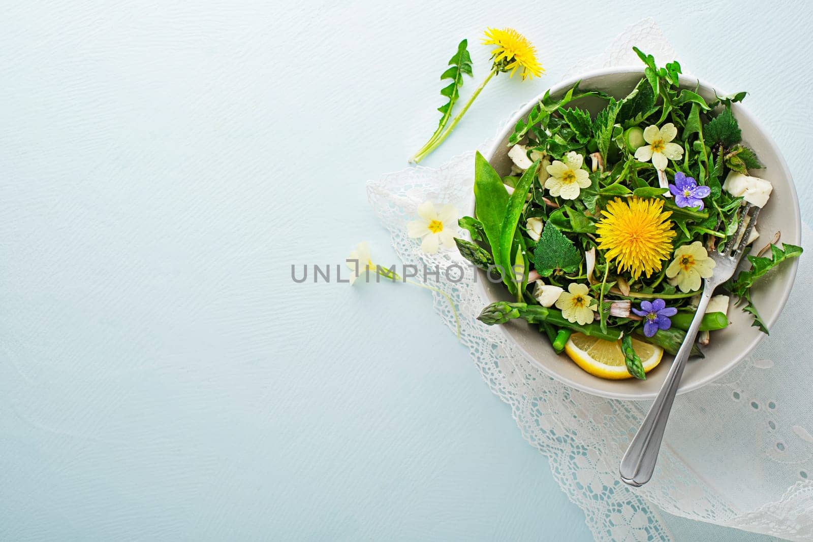 Spring salad with dandelion, asparagus, wild garlic, flowers, nettle and cream cheese. Healthy spring detox food ingredients.