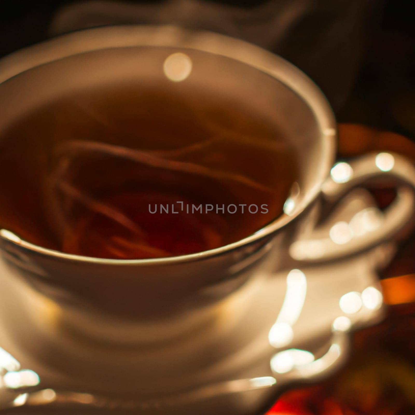 Cup of a hot tea in cafe. Anamorphic bokeh effect. Tilt-shift photo. Tasty aromatic tea in a lovely cup with a saucer. The tea is getting cold. Natural aroma. Label or advertisement. Evaporation