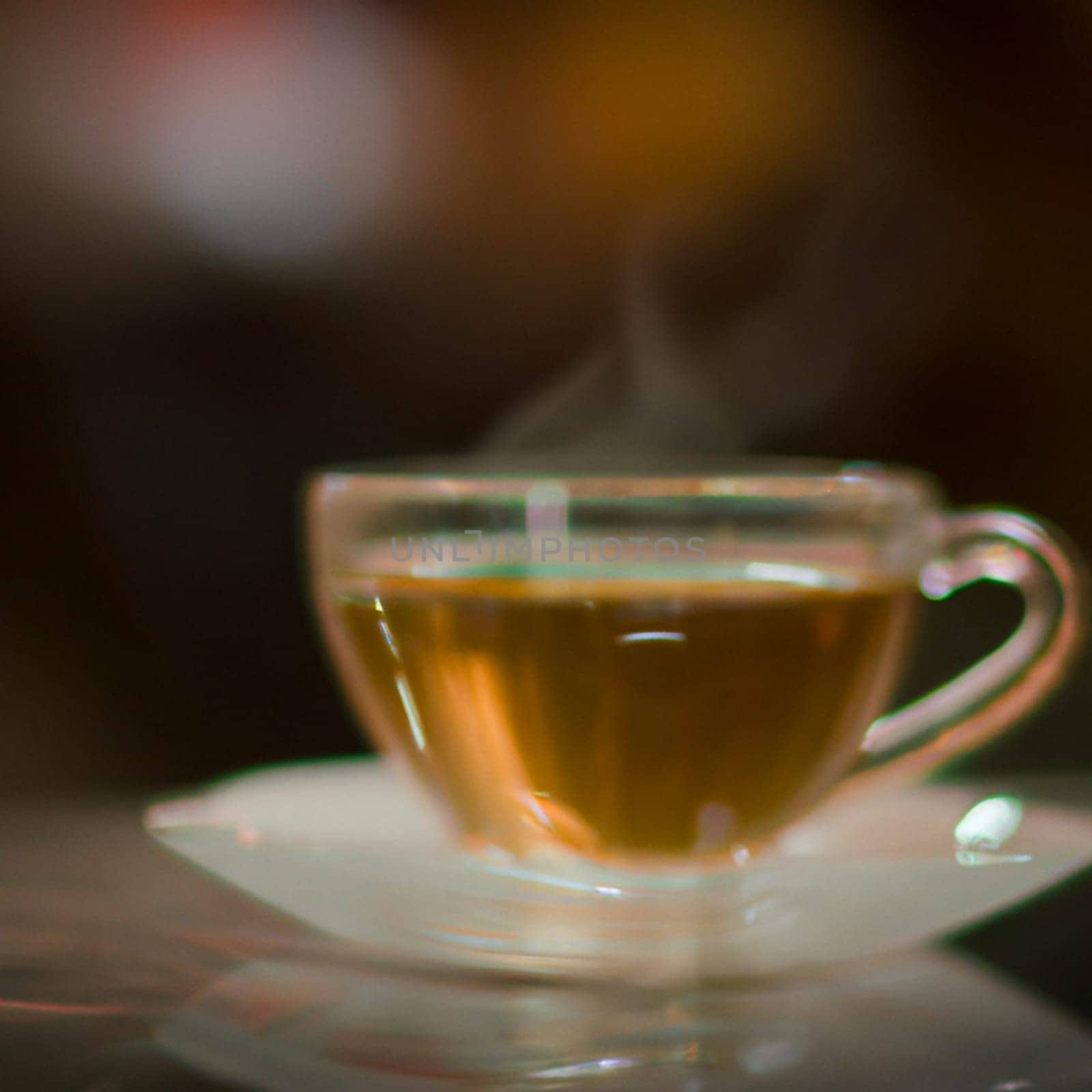 Cup of a hot tea in cafe. Anamorphic bokeh effect. Tilt-shift photo. Tasty aromatic tea in a lovely cup with a saucer. The tea is getting cold. Natural aroma. Label or advertisement. Evaporation