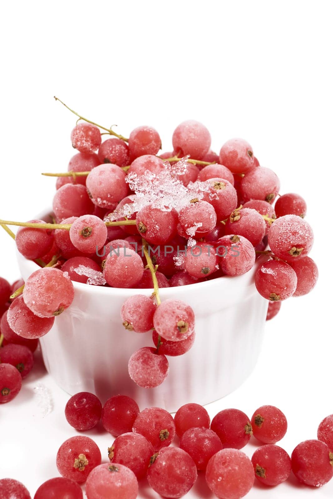 Frozen currants with stems in porcelain bowl
