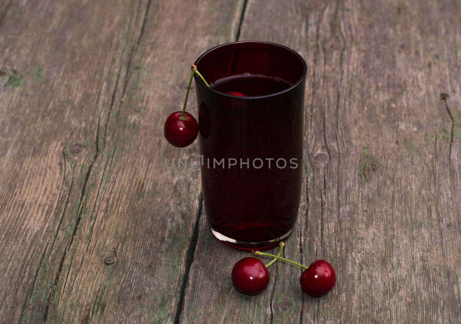 the glass of juice decorated with berries of red sweet cherry, the image of drink