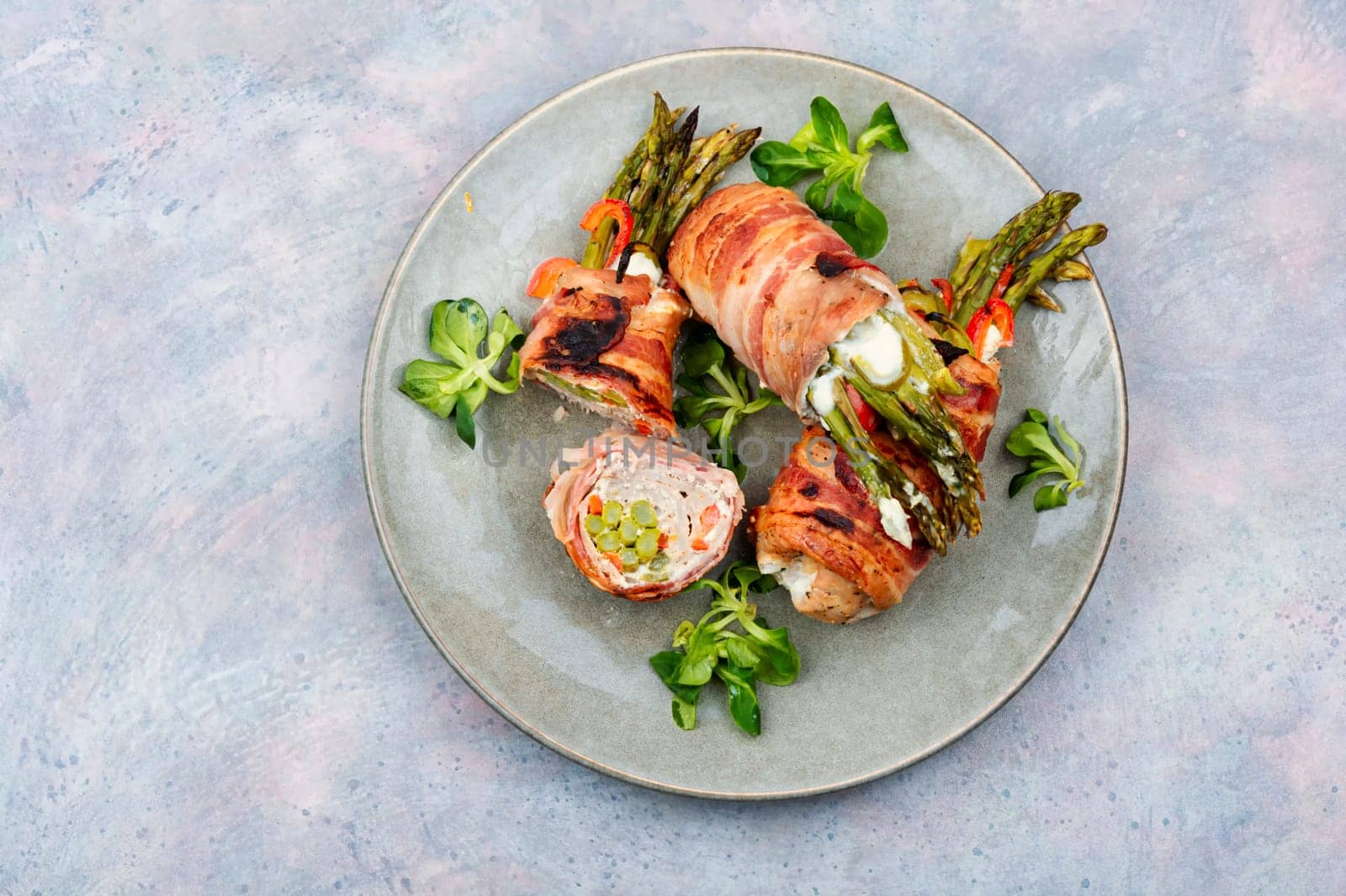 Meatloaf wrapped in bacon. Roasted green asparagus wrapped with meat . Top view
