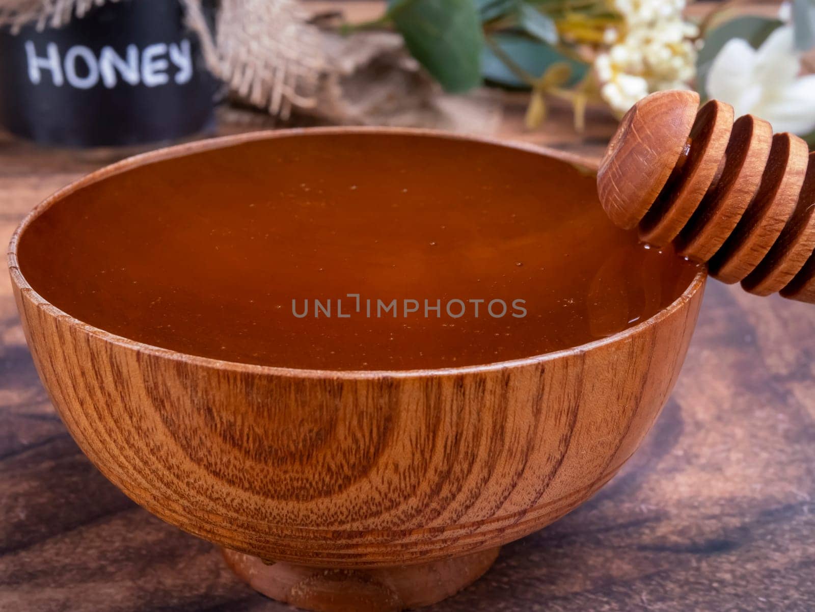 Honey spoon coming out of the bowl full of honey. Honey contains many nutrients, antioxidants, improves heart health, wound care, offers antidepressant and anti-anxiety benefits.