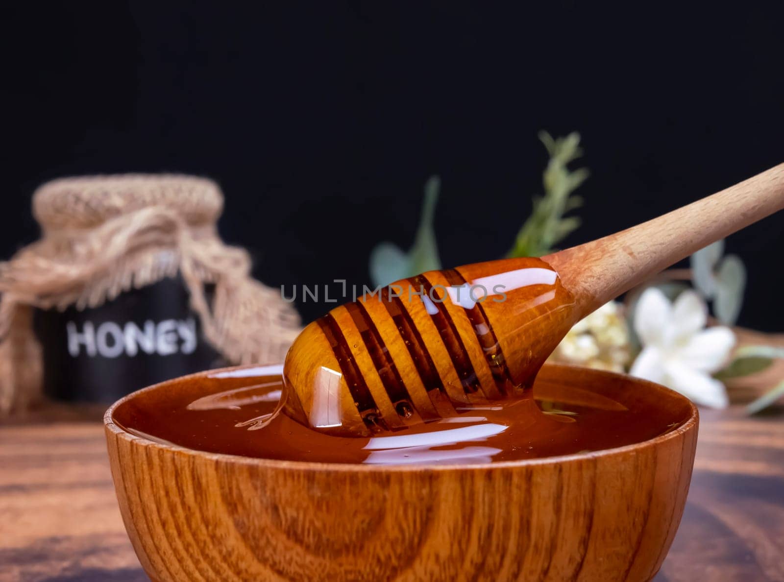 Honey spoon coming out of the jar full of honey. Honey contains many nutrients, antioxidants, improves heart health, wound care, offers antidepressant and anti-anxiety benefits