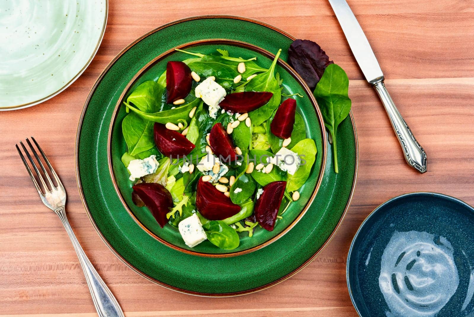 Fresh salad with beets, blue cheese, herbs and pine nuts on the plate. Healthy food