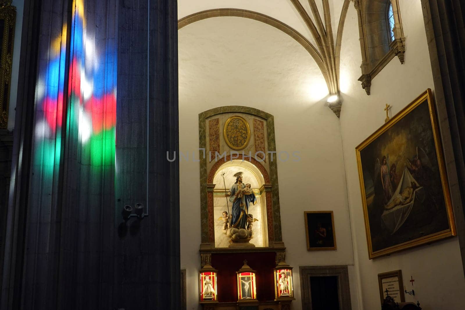 Innenansicht der Santa Ana Kathedrale - Buntglasfenster werfen Farben auf einen Pfeiler an einem Seitenaltar, Gran Canaria, Spanien, Las Palmas