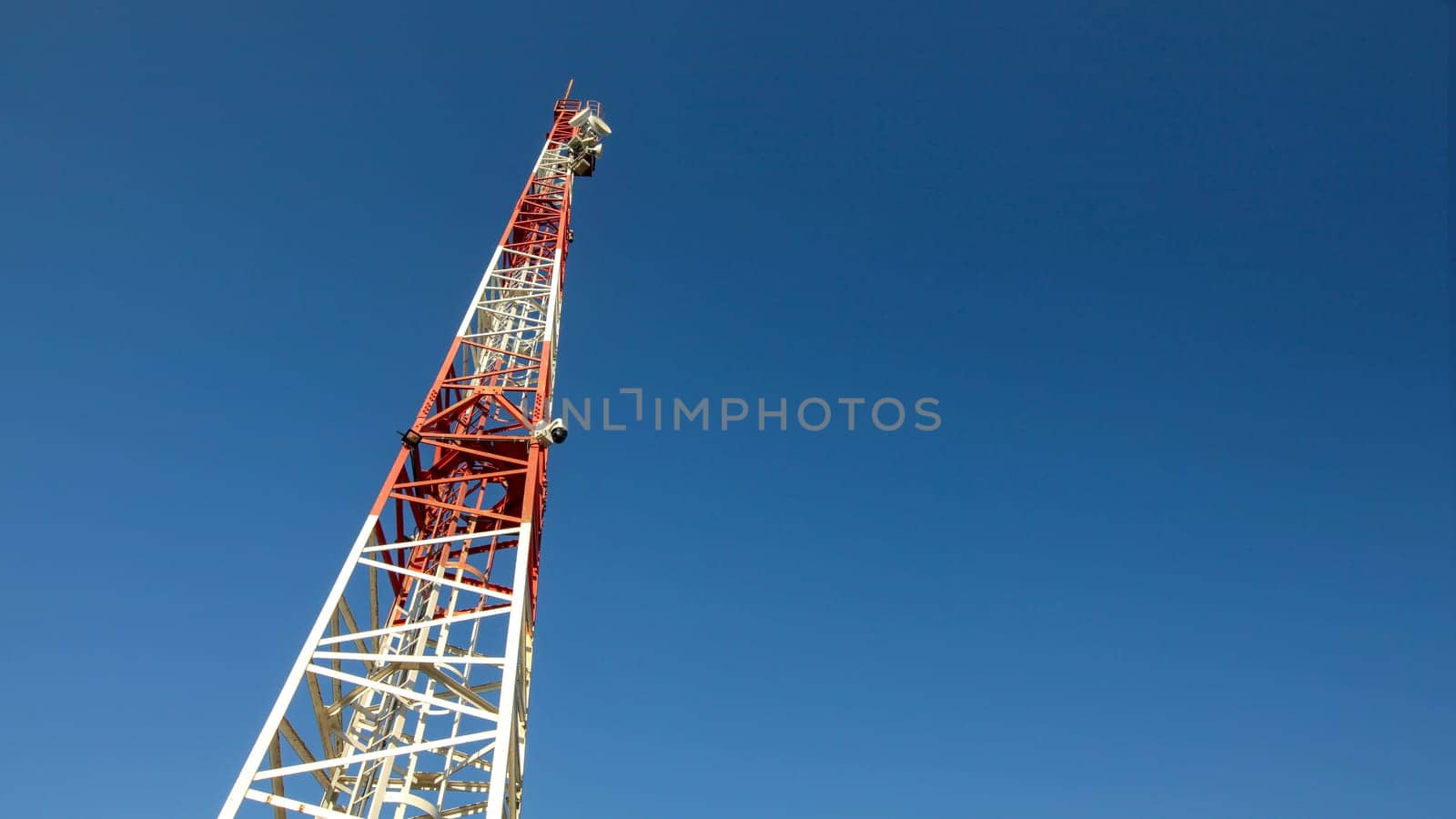 Looking up to small red and white telecommunications tower, communication dishes on top. Abstract technology background, space for text on right.
