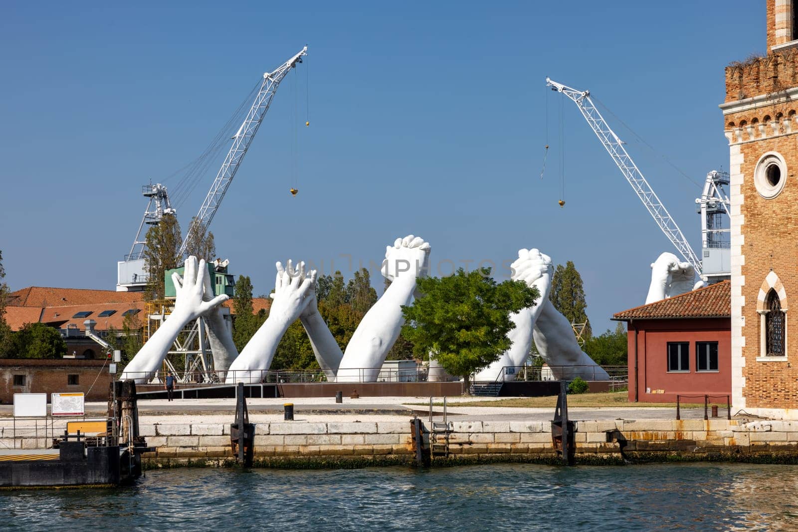 Venice, Italy - September 6, 2022: Giant joined hands sculpture Building Bridges by Lorenzo Quinn. Exhibition at Arsenale, Castello, Venice