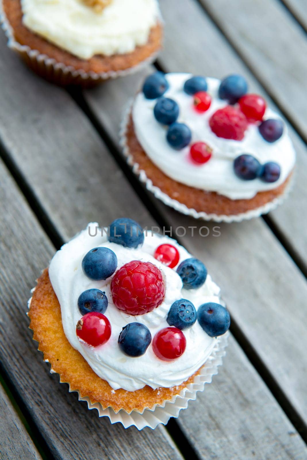 muffins on wooden ground with blueberry, raspberry and whipping cream