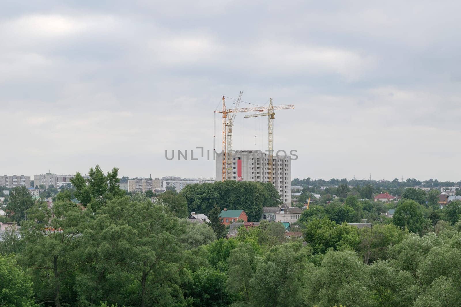Three high tower crane building a new house flats in a beautiful green park area of the city.
