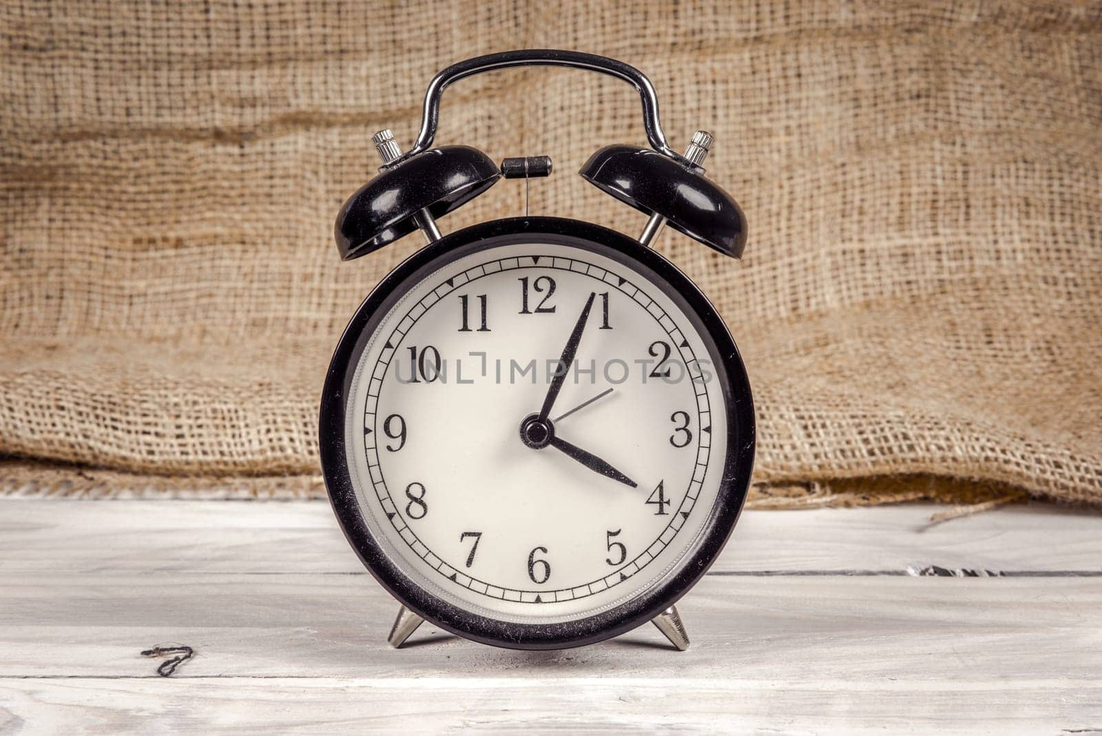 Classic black and white alarm clock on a wooden table