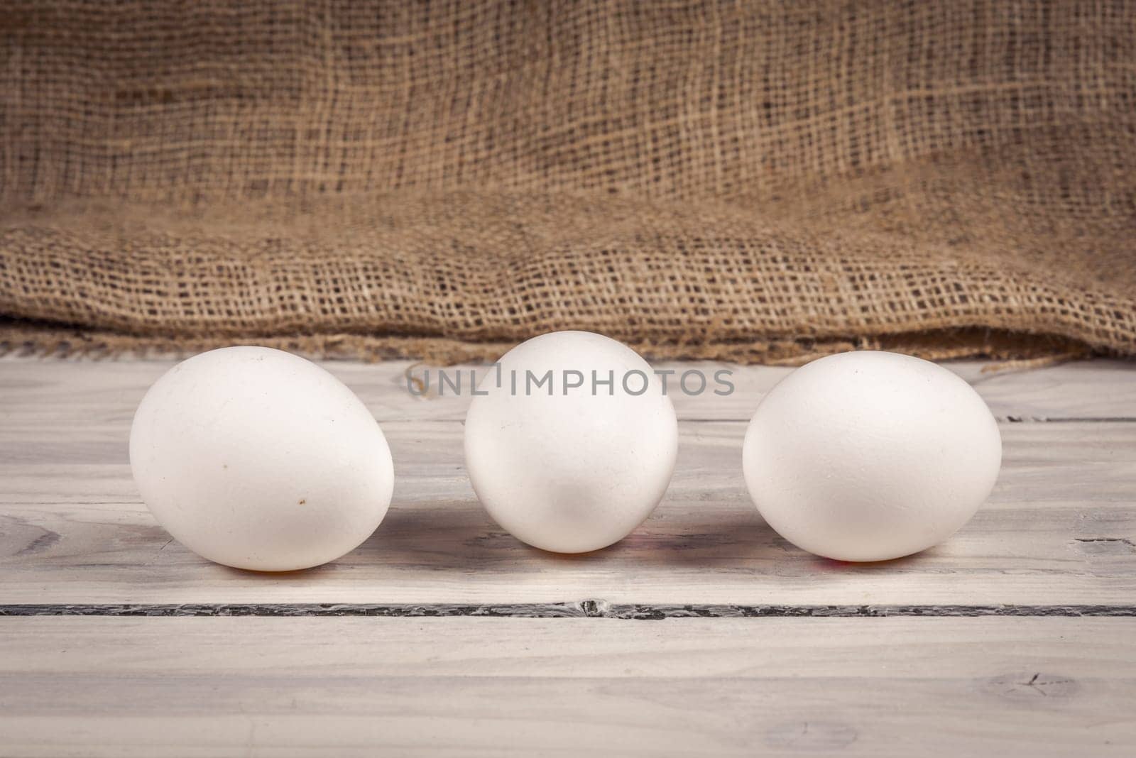 Three white eggs on a old wooden table