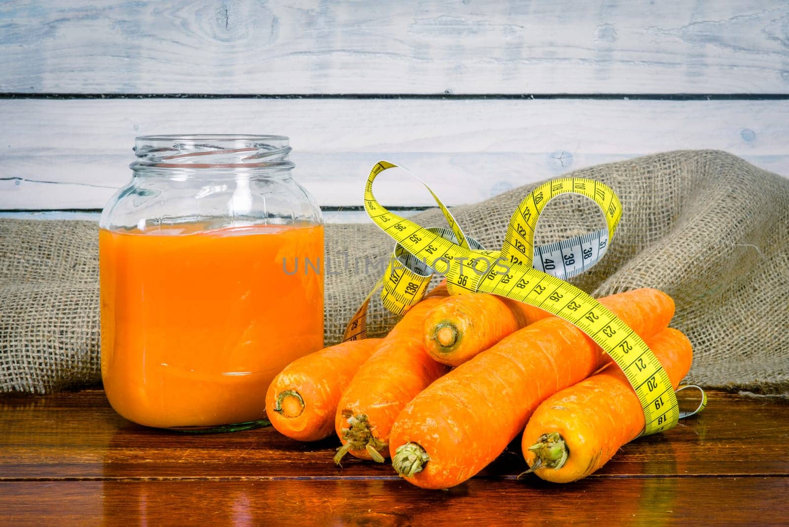 Carrots and juice on a wooden table with measure tape