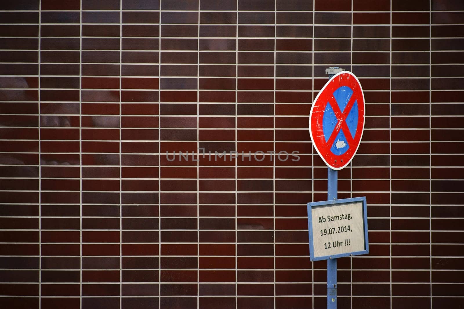 An old and dented stop sign stands in front of a striking brick facade.