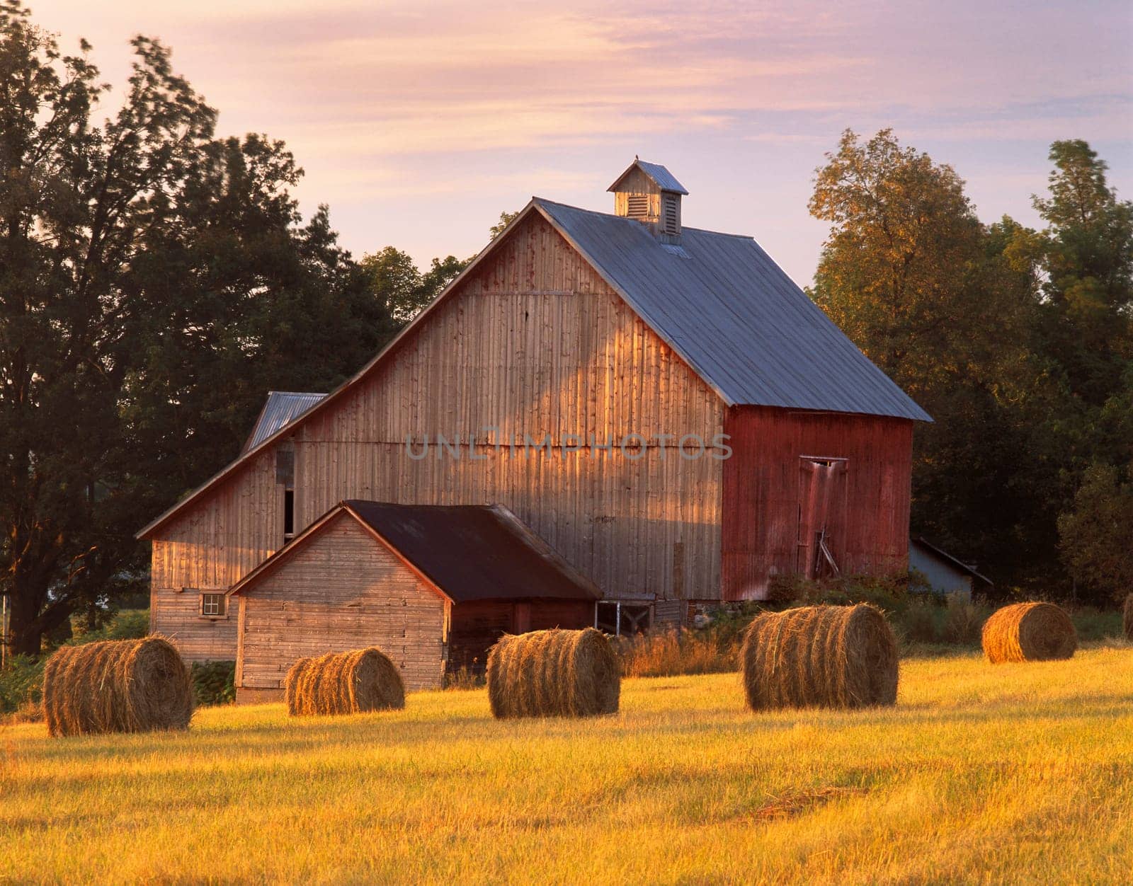 A barn in N. Hero, Vermont with round bales of hay.
